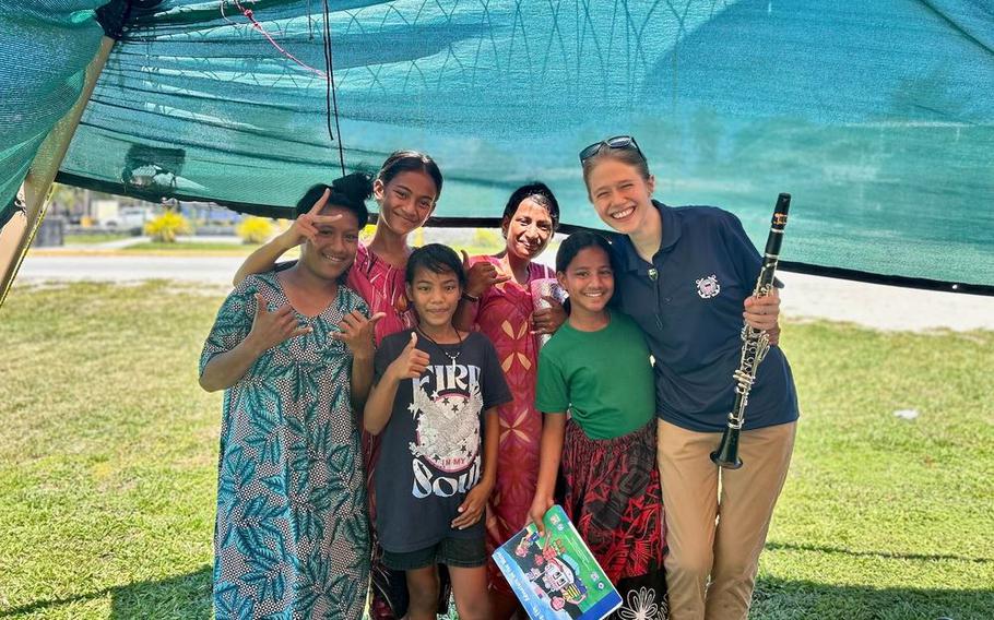 A member of the U.S. Coast Guard Band stands with locals after a performance at Delap Park in Majuro, Republic of the Marshall Islands.