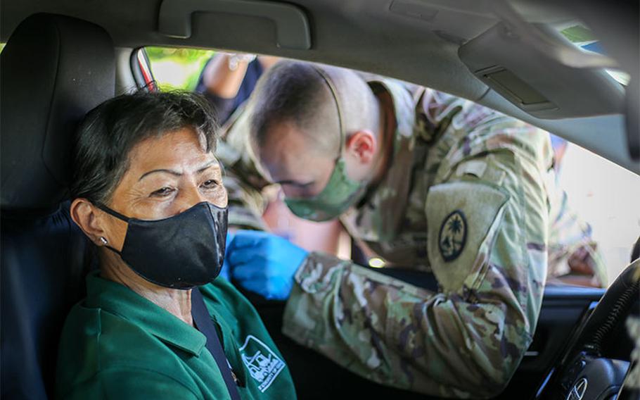 Spc. Michael Marsh of the Guam National Guard's Task Force Medical, right, administers a COVID-19 vaccination shot to a member of the community during a Strike Team community outreach point of distribution at the Port Authority of Guam in Piti on June 2, 2021.