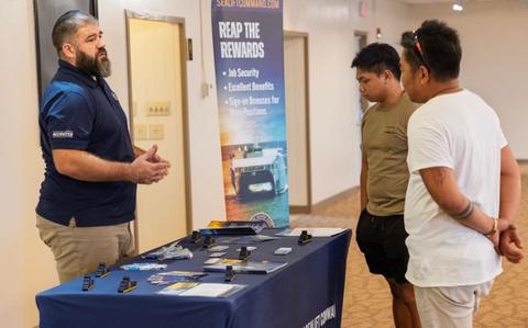 Photo Of Michael Mack, field recruiter, Military Sealift Command, speaks to interested applicants at a job fair in the Top o’ the Mar reception center at the Nimitz Hill Annex, in Asan, Dec. 11.