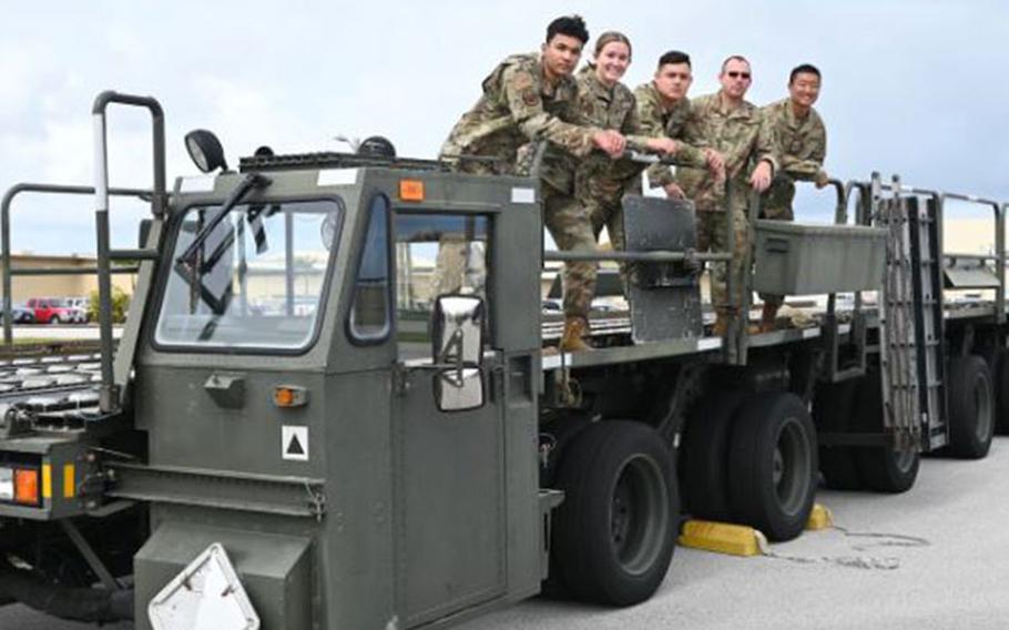 Airmen from the 36th Logistics Readiness Squadron pose on a container loader for a group picture at Andersen Air Force Base, December 15th, 2021. The Airmen formed a last minute cargo load team in support of an emergency delivery of Reverse Osmosis Water Purification Units to Wake Island after their water purifier malfunctioned, leaving the atoll without potable water. (U.S. Air Force photo by Staff Sgt. Nicholas Crisp)