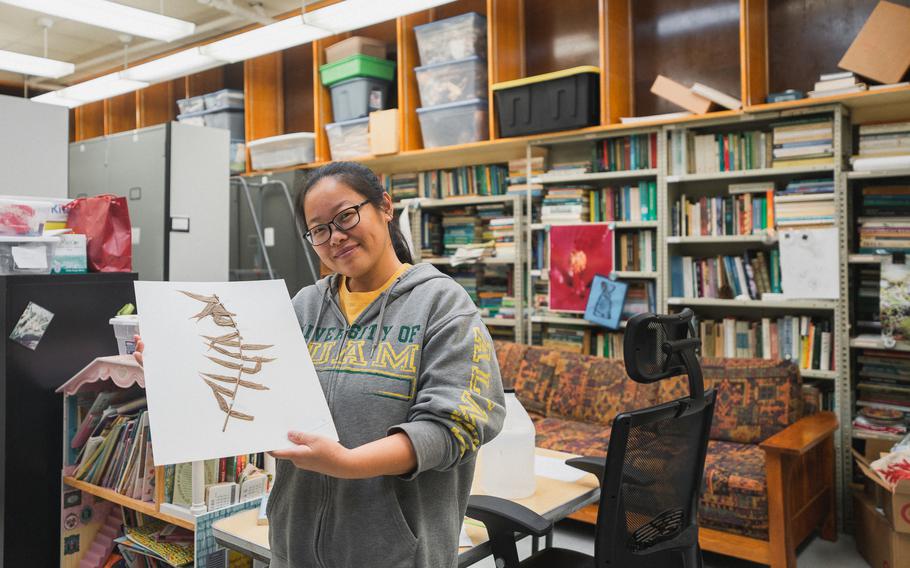 Wei Xiao, curator of the University of Guam Herbarium, holds a specimen sheet of a local plant. The herbarium holds 60,000 sheets like this one and is embarking on an effort to get them all uploaded to a virtual database that can be searched and accessed worldwide.