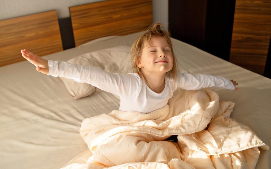 Girl sits on the bed in the early morning