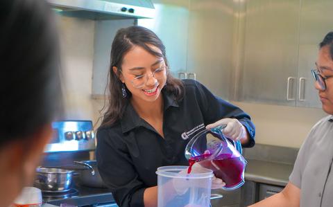 Photo Of Sophie Santos, an extension associate with UOG Land Grant, pours fresh dragon fruit nectar during a value-added foods workshop.