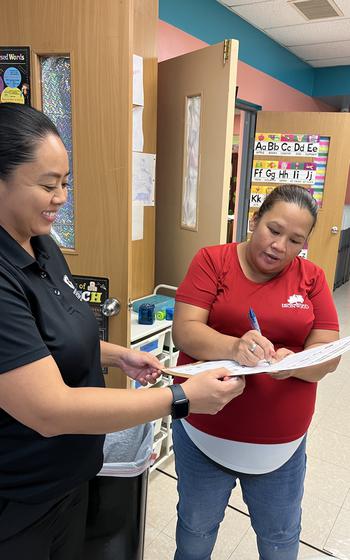 Crystal Guevara, program coordinator at Ironwood Heights Community Center, signs the 5-2-1-Almost None pledge while Rynette Perez, assistant coordinator of the SNAP-Ed program under UOG Cooperative Extension & Outreach, looks on at a ceremony on Sept. 23, 2024.