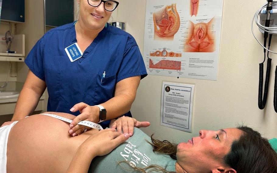 A certified nurse midwife at Naval Hospital Jacksonville, uses a tape measure to determine fetal height on a maternity patient during a prenatal examination.