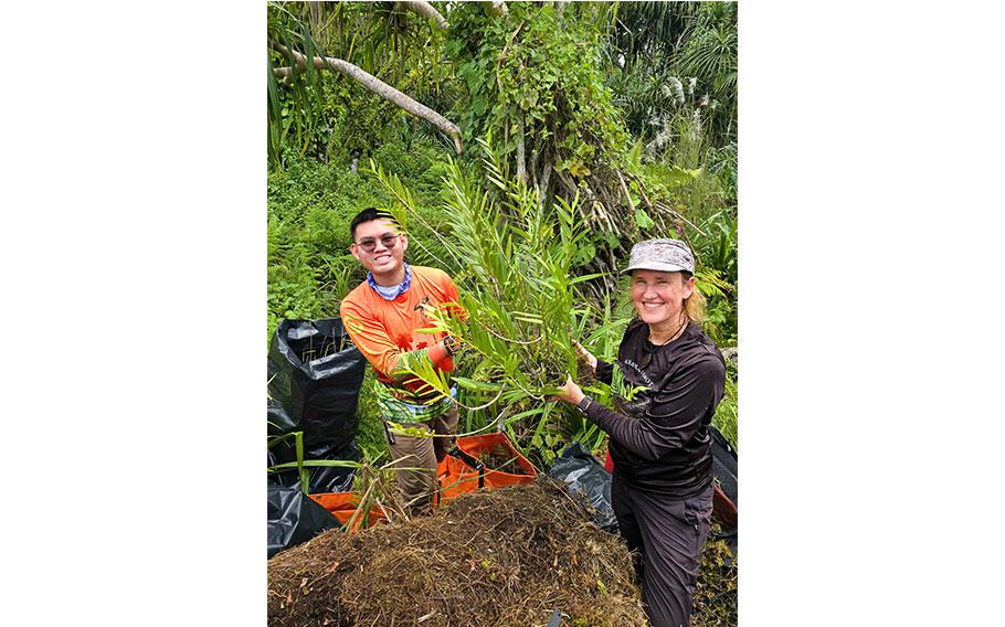 Vince Fabian and Else Demeulenaere, Ph.D., (UOG CIS & SG, Island Conservation Lab) hold a Dendrobium guamense after detaching it from a tree.  