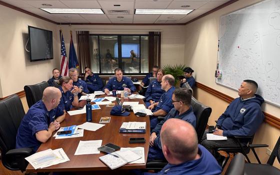 Photo Of Members of U.S. Coast Guard Forces Micronesia/Sector Guam and Base Guam conduct a storm briefing in a meeting room with a whiteboard.