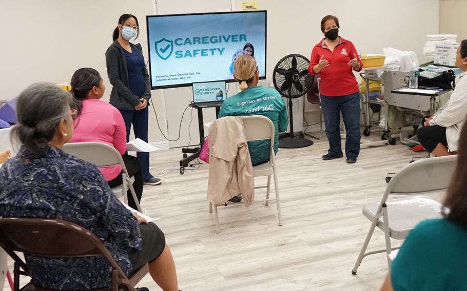 Veronica Alave (standing, right), a Dementia Capable Care certified instructor and instructor of Nursing at Margaret Perez Hattori-Uchima School of Health at the University of Guam, presents during an in-person caregiver session hosted by the Guam/Micronesia Geriatrics Workforce Enhancement Program. During the session, participants learned about proper repositioning/body mechanics and safe shower and bed bath practices in this file photo from a training session in 2023.