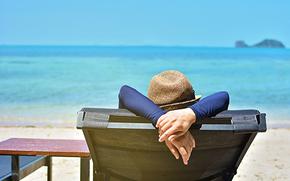 Woman relaxing on a tropical beach with hat.