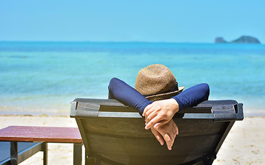 Woman relaxing on a tropical beach with hat.