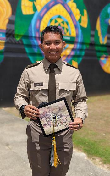 UOG Senior Army ROTC alumnus 2LT Lidio Fullo stands in front of a mural.