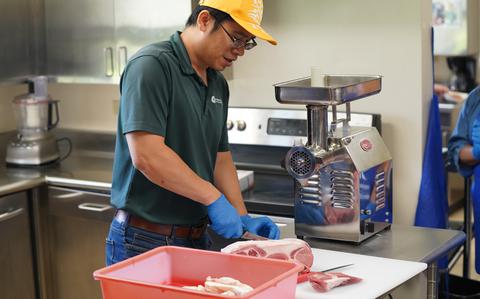 Photo Of One of the participants cut meat in the kitchen.