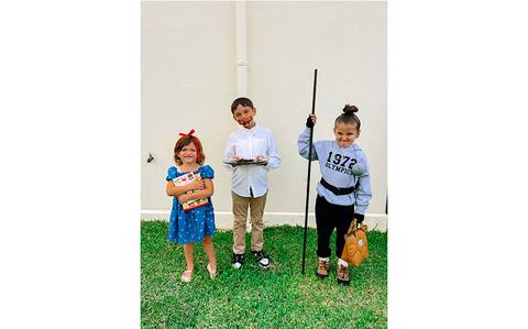 Photo Of three kids with halloween costumes on the lawn.