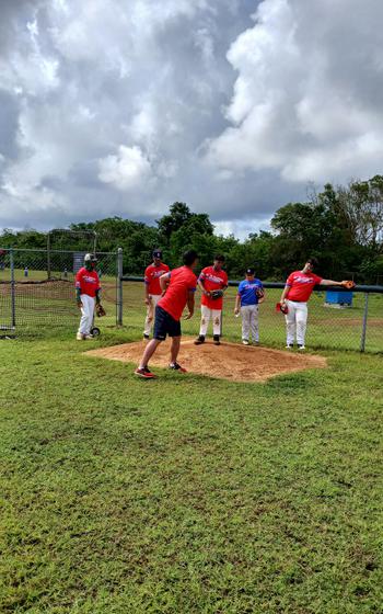 A coach teaching how to pitch.