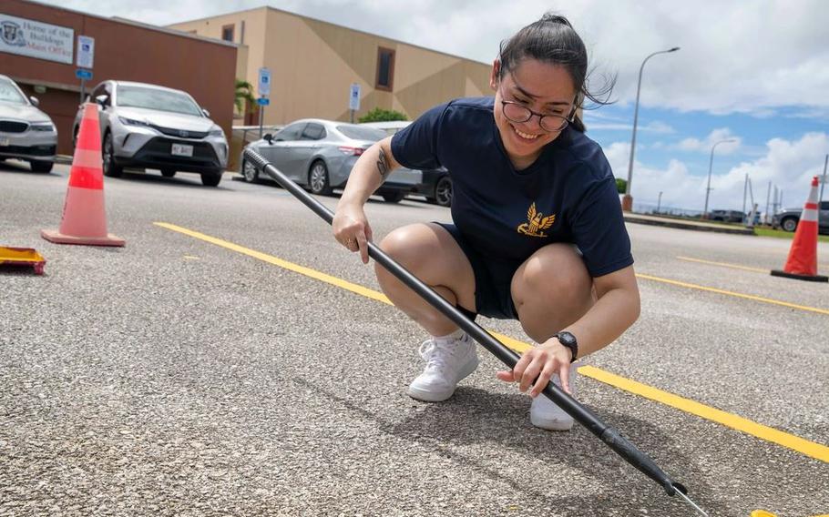 Hospital Corpsman 3rd Class Amya Huey paints a parking lot during a community relations project at Okkodo High School in Guam.
