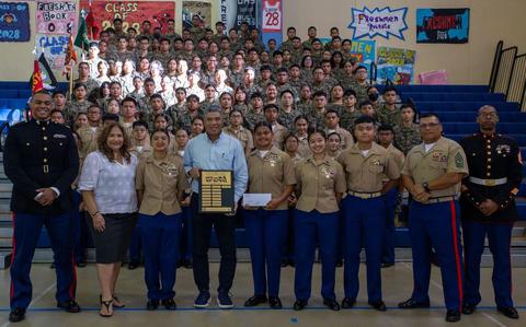 Photo Of U.S. Marines with Marine Corps Base Camp Blaz, a senior leader with the Marine Corps Junior Reserve Officers’ Training Corps, members of the Guam Chamber of Commerce, and students with the Marine Corps JROTC pose for a group photo at Okkodo High School, Dededo, Guam, Jan. 24, 2025. High schools on Guam participated in a toy collection challenge for Toys for Tots. The high schools that collected the most toys were rewarded with a check from the Guam Chamber of Commerce and the schools name on a Toys for Tots plaque.