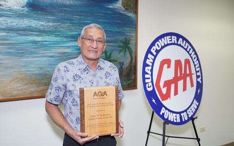 Photo Of GPA GM John M. Benavente, P.E. holds the award by the wall.