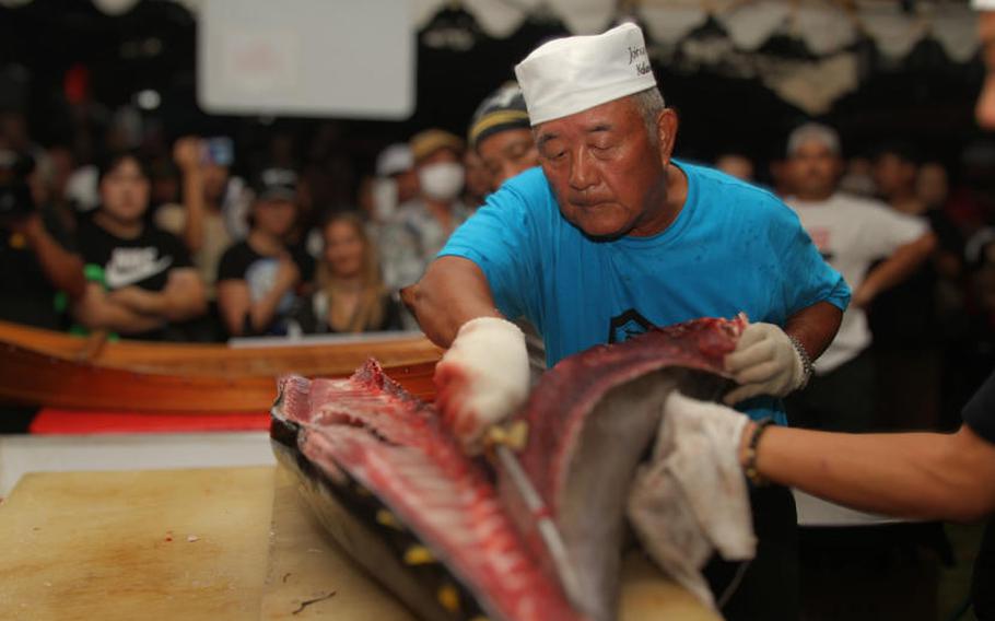 a man is cuttinga tuna fish.