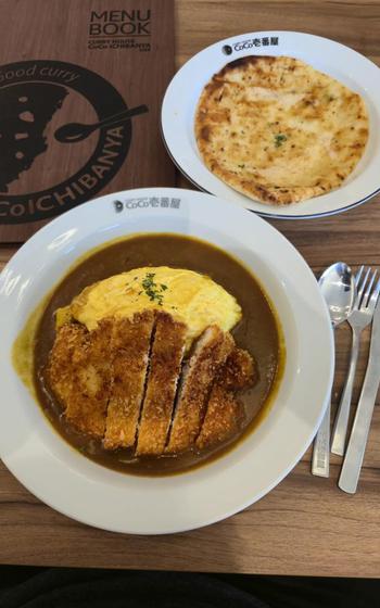 Curry and cutlet, and naan on the table.