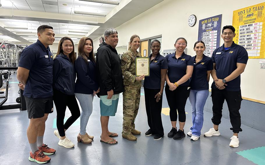 Charles King Fitness Center & Pool group photo as Stars and Stripes Pacific Commander Lt. Col. Marci Hoffman presents Best fitness center award to Charles King Fitness Center & Pool staff