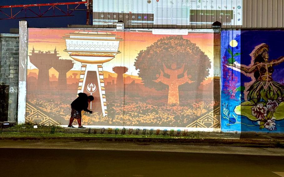 Guam Green Growth Art Corps member Kie Susuico works on outlining his design on a wall in Sinajana. Members for the Cohort Two will also be creating murals in the various villages on Guam.