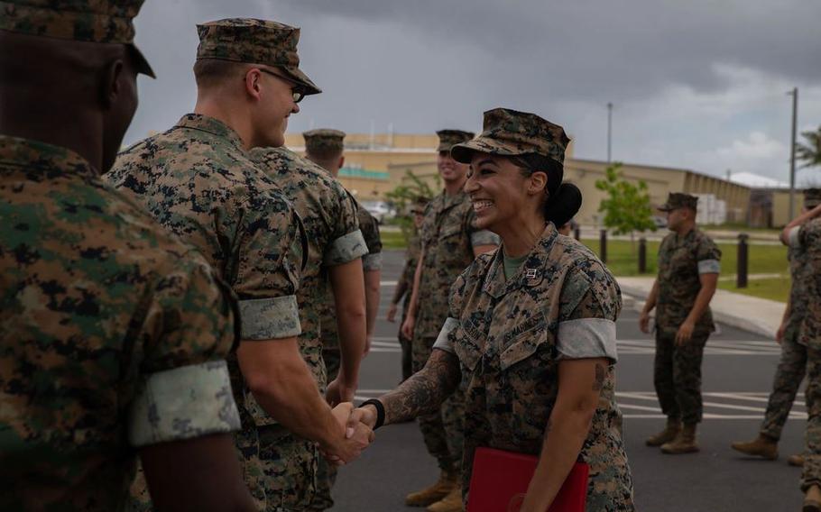 U.S. Marines congratulate Capt. Lara DeLeon smilingly shakes hands with some other military personnel.