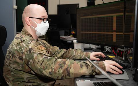 Photo Of Senior Airman Andrew Vance with mask is typing in the office.