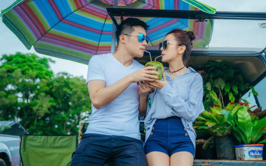 a couple is sharing coconut juice.