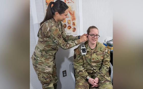 Photo Of U.S. Air Force Capt. Emily Lee checks the ear of fellow audiologist Capt. Jacqueline Anderson in the chair.