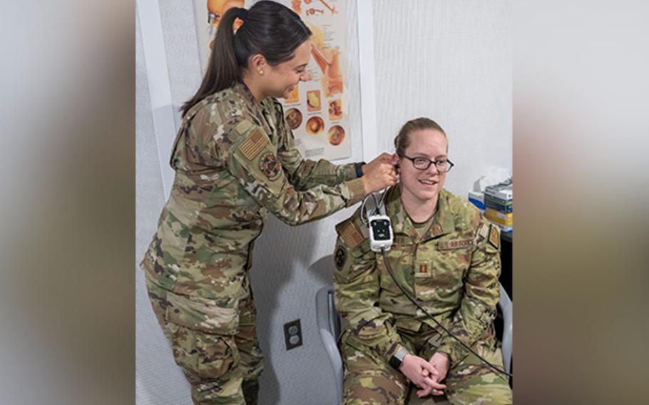 U.S. Air Force Capt. Emily Lee checks the ear of fellow audiologist Capt. Jacqueline Anderson in the chair.