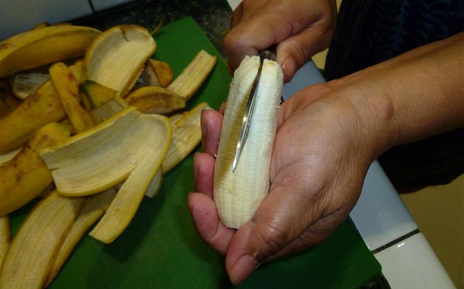 a person is cutting a banana into two.