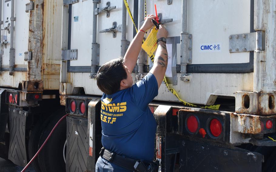 A Guam Customs and Quarantine Agency Biosecurity Task Force officer removes the agency’s protective seal from a shipping container of fresh Christmas trees prior to a scheduled fumigation treatment and inspection on Dec. 2, 2024 at a local business establishment in Tamuning.