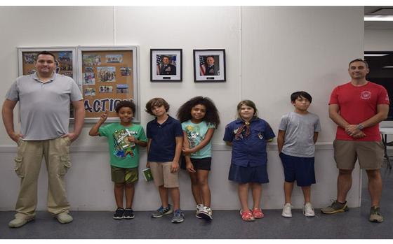 kids and adults pose in front of a wall.