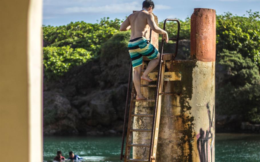 a man climbing a ladder in Inarajan Natural Pool.