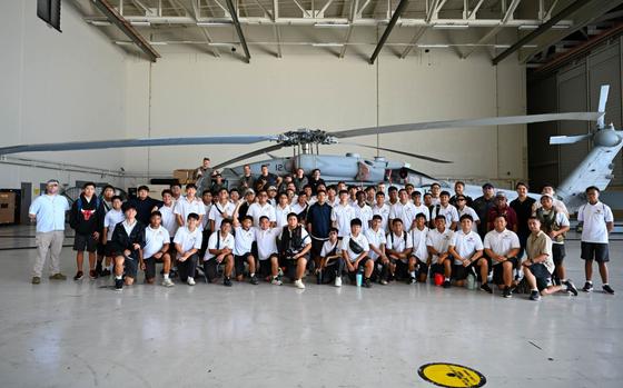 U.S. Navy Helicopter Sea Combat Squadron 25 members pose for a group photo with Father Duenas Memorial School Junior Reserve Officers’ Training Corps students during a base tour at Andersen Air Force Base, Guam, May 2, 2025. HSC-25 members showcased the MH-60S Sea Hawk while explaining day to day life as pilots, rescue swimmers, maintenance and more as part of a base tour. 