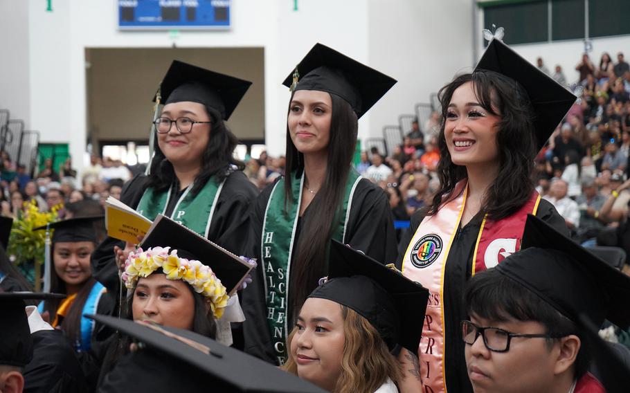 Health science majors Francesca Dean, left, and Alexandra Lekites, center, and social work major Ally Sablan stand for the presentation of degree candidates from the School of Health.