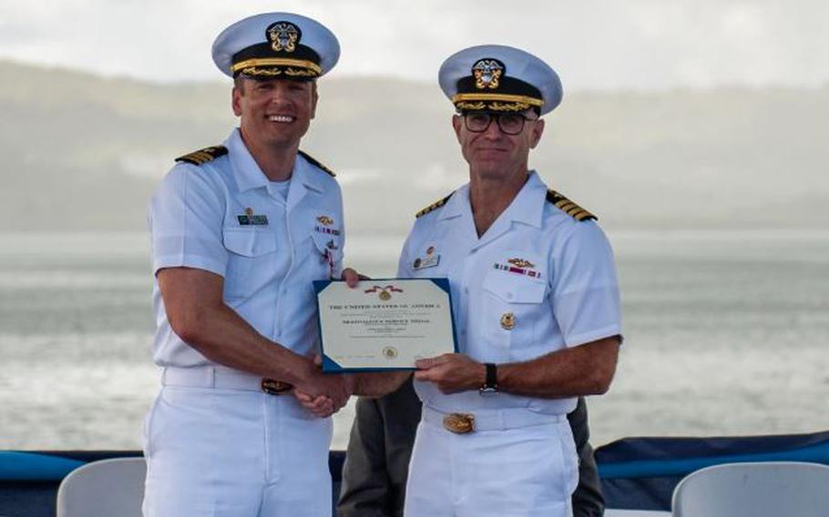 Cmdr. Andrew Domina, commanding officer of the Los Angeles-class fast-attack submarine USS Springfield (SSN 761), left, receives an award from Capt. Neil Steinhagen, commander, Submarine Squadron 15, during a change of command ceremony, July 30.