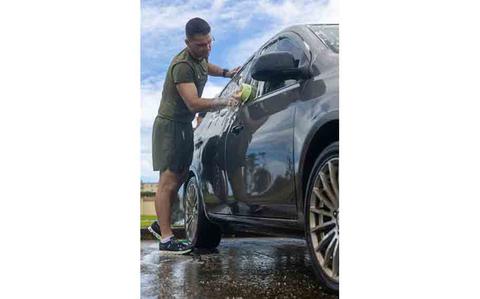 Photo Of U.S. Marine Corps Lance Cpl. Thomas Hackney, network administrator, Headquarters Company, Marine Corps Base Camp Blaz, washes a car during a car wash fundraiser to raise money for the 250th Marine Corps ball.