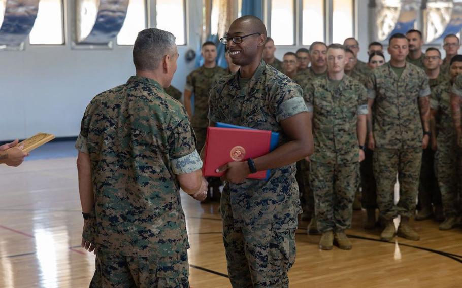 U.S. Marine Corps Staff Sgt. Marcellous Dixon, training chief, Marine Corps Base Camp Blaz, shakes hands with Col. Ernest Govea, commanding officer, MCB Camp Blaz, during an award ceremony.