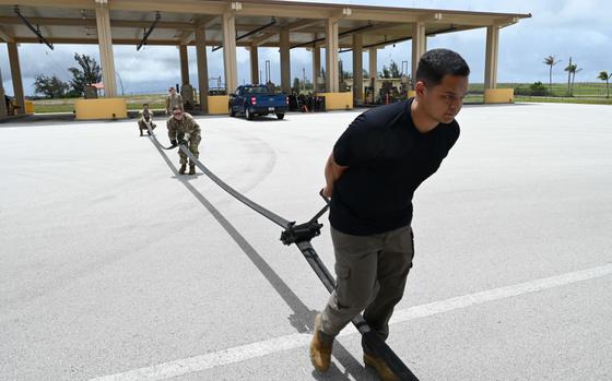 Photo Of Tech. Sgt. Matthew Perlongo (left), 36th Logistics Readiness Squadron noncommissioned officer in charge of Fuels Support anchors one end of a Versatile Integrating Partner-Nation Equipment Refueling hose, while Tech. Sgt. Jennifer Barnett (mid), 36th LRS NCO in Charge of Fuels Distribution lifts and follows David Conceicao, 36th LRS Fuels Equipment maintainer, who is using a squeegee to recover any fuel remaining in the hose at Andersen Air Force Base, July 10, 2024.