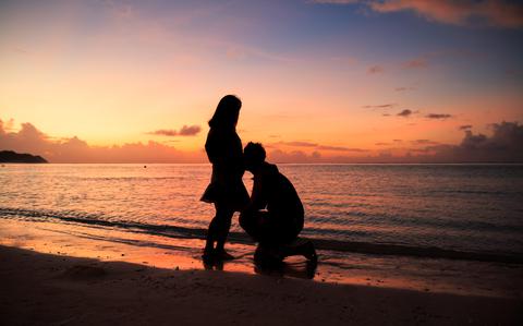 Photo Of silhouette of couple on the beach with a beautiful sunset in background